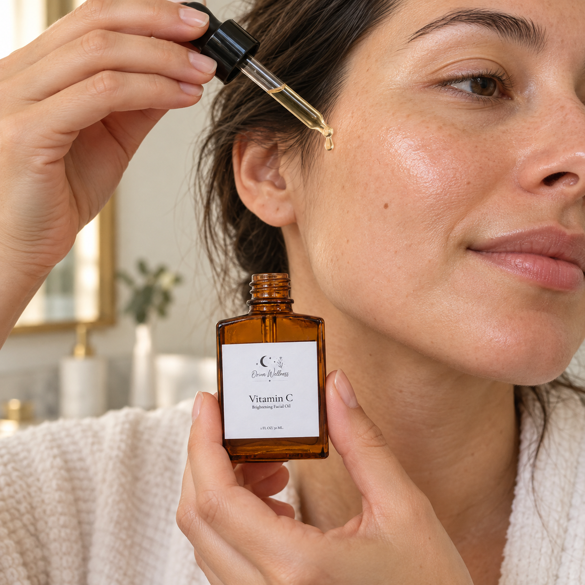 Vitamin C Brightening Facial Oil being applied to the cheek with a glass dropper, showing the small 1 oz bottle held in one hand