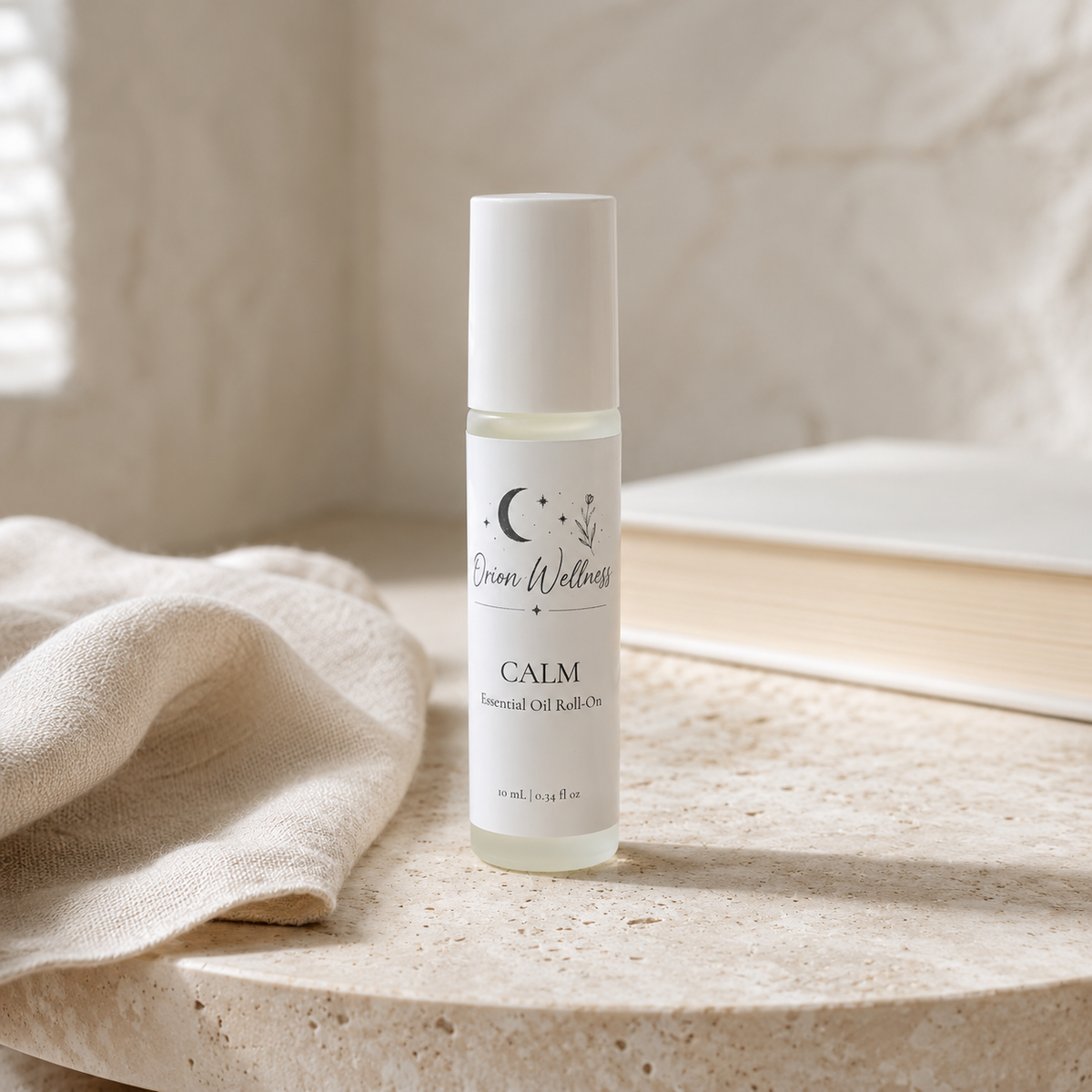Orion Wellness Calm roll-on on a pale stone table beside natural linen and an ivory book.