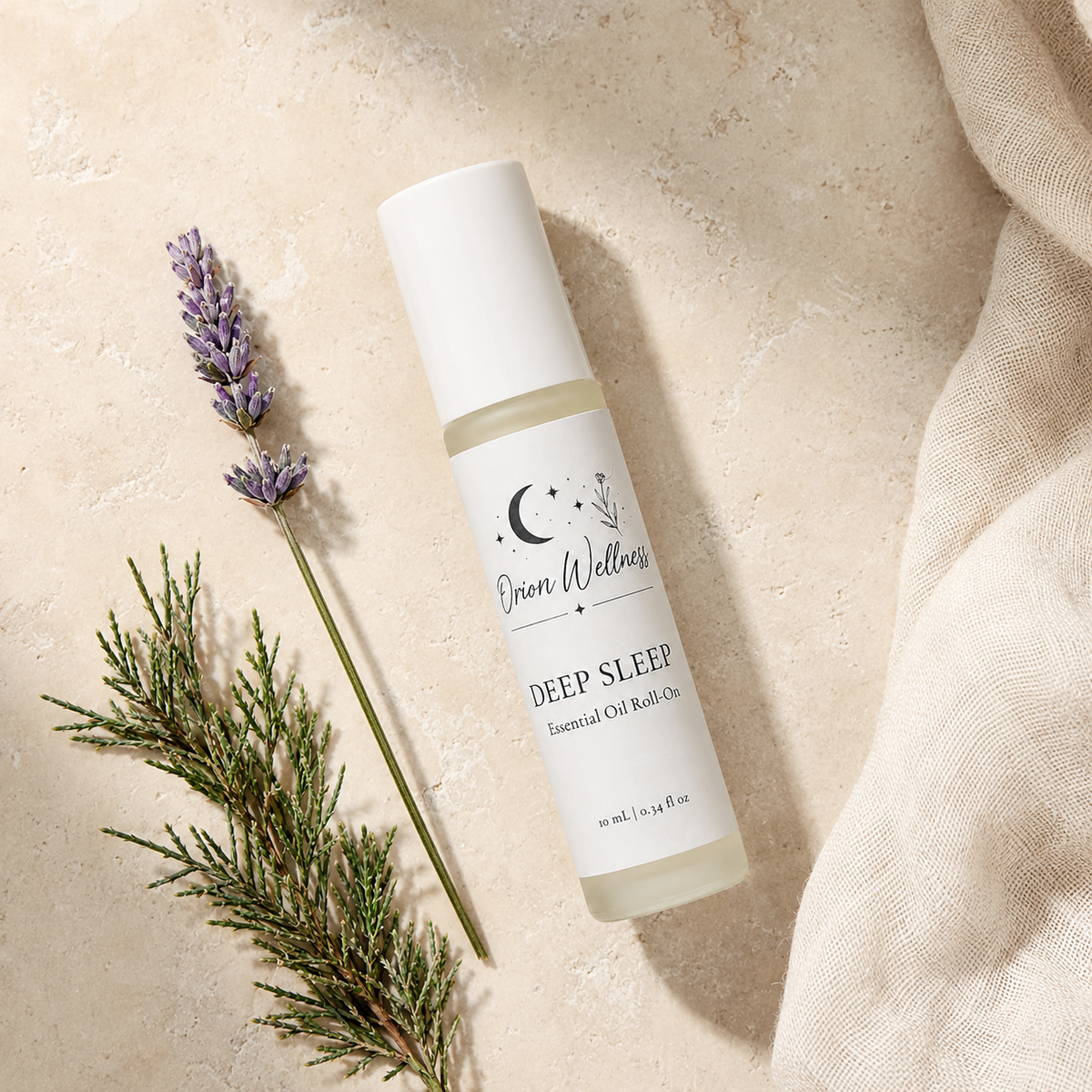 Orion Wellness Deep Sleep 10 mL roll-on on pale stone beside lavender, evergreen greenery, and natural linen.