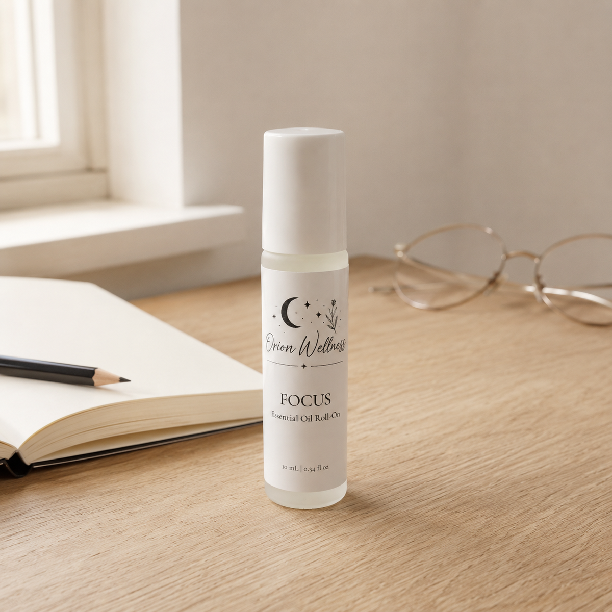 Orion Wellness Focus roll-on on an oak desk beside an open notebook, pencil, and reading glasses.