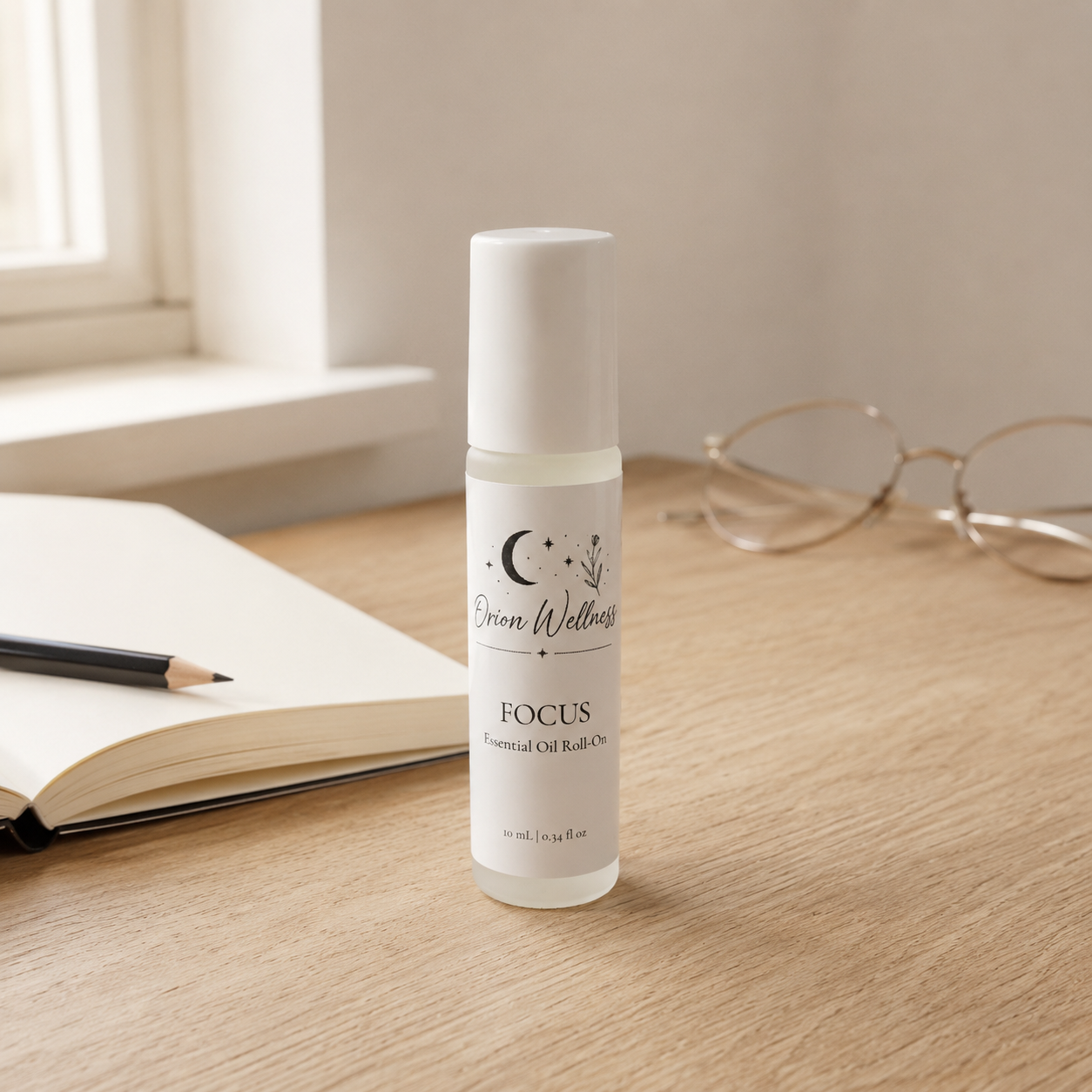Orion Wellness Focus roll-on on an oak desk beside an open notebook, pencil, and reading glasses.