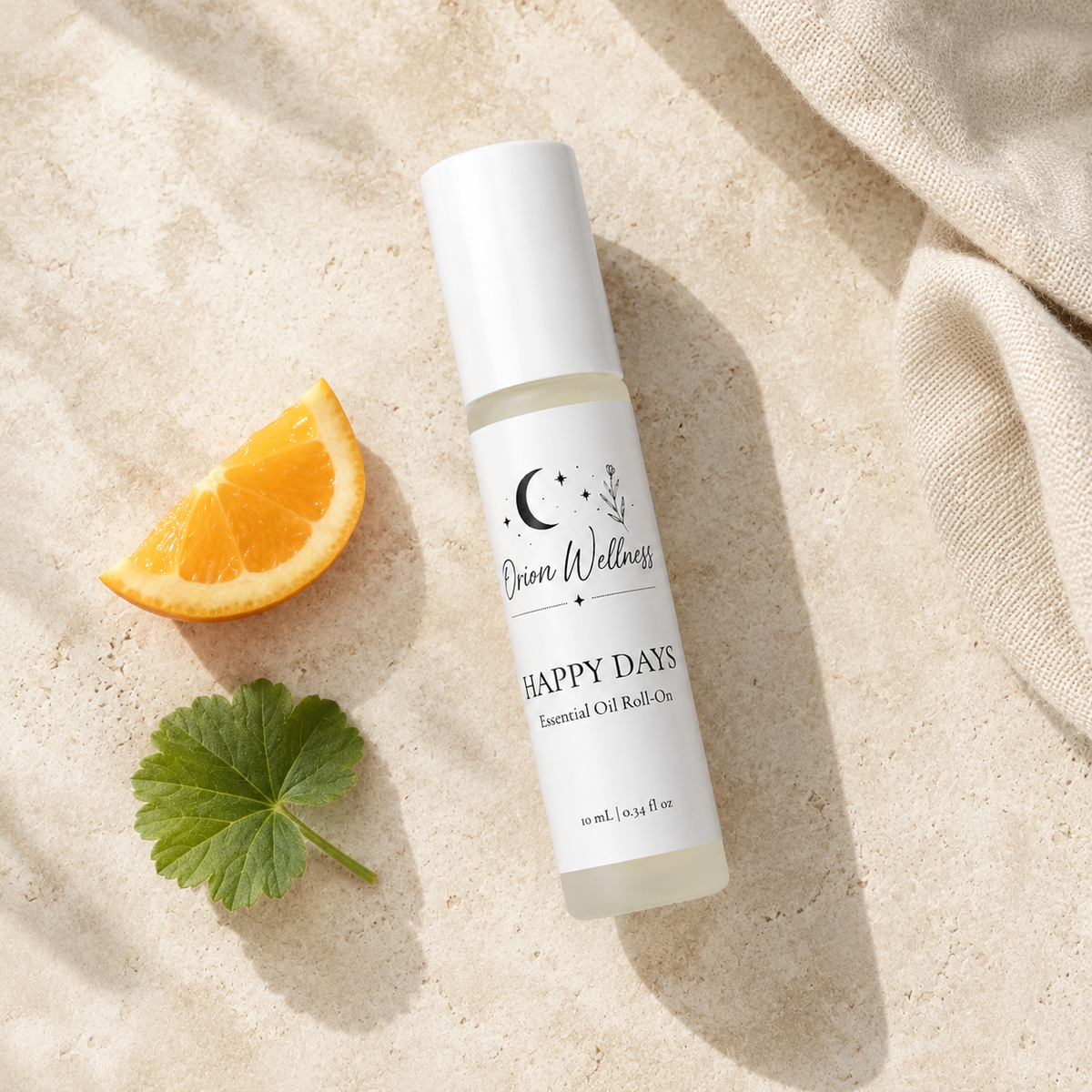 Orion Wellness Happy Days 10 mL roll-on on pale stone beside an orange wedge, a geranium leaf, and ivory linen.