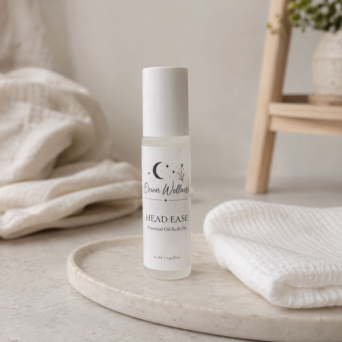 Orion Wellness Head Ease roll-on on a pale stone tray beside a folded white washcloth.
