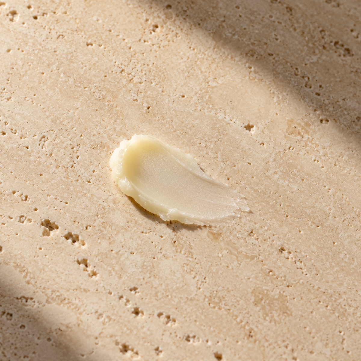 Orion Wellness lip balm styled texture illustration on warm travertine